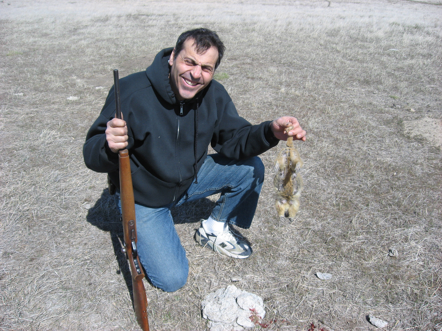 Man with a riggle holding a deat rodent